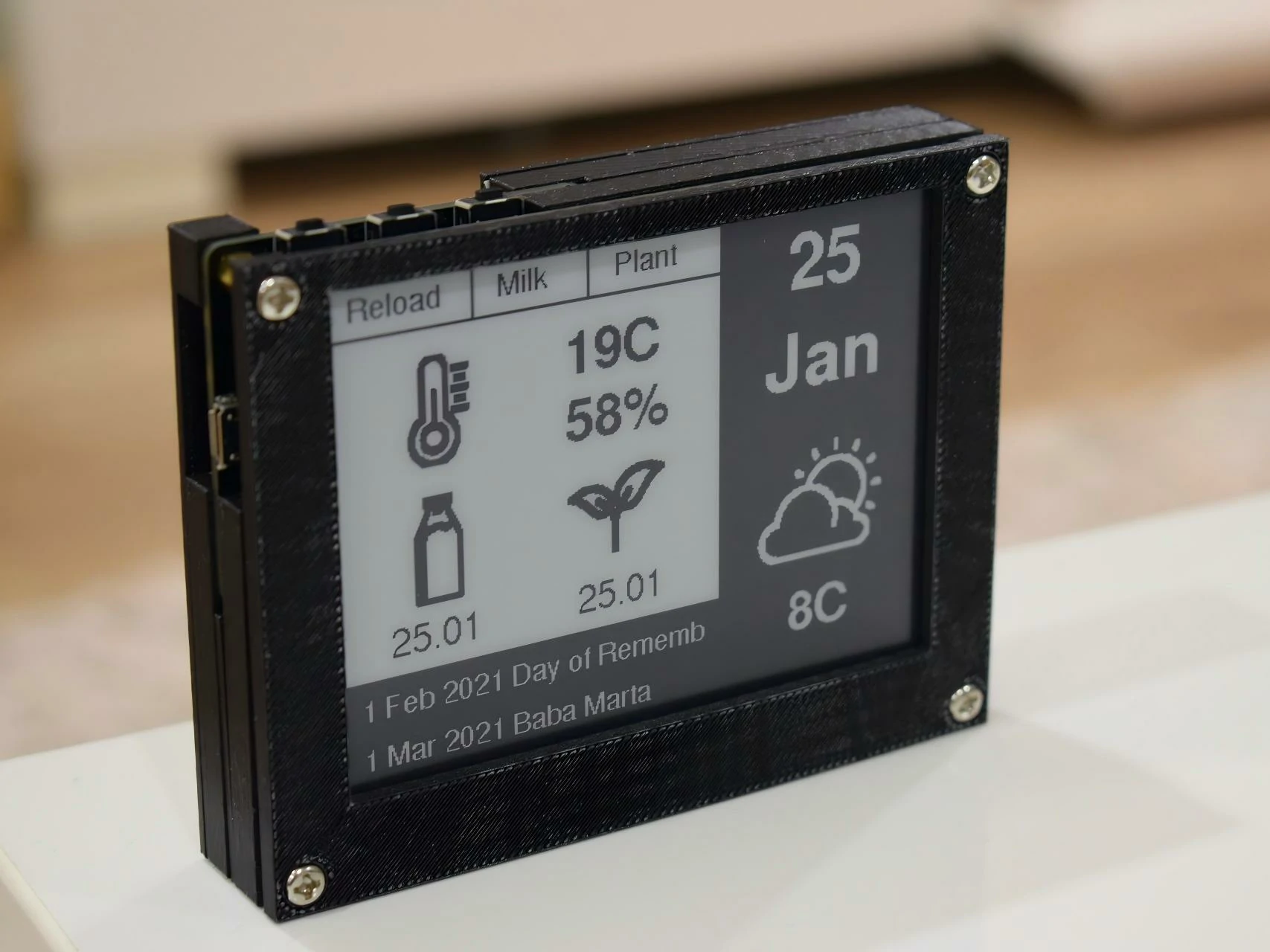 Small ePaper information display in a black enclosure showing date and readings